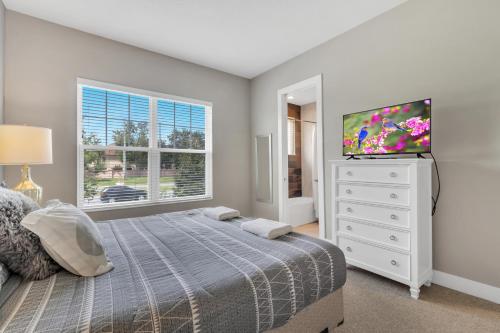 1 dormitorio con 1 cama y TV de pantalla plana en Lovely 4 Bedrooms, 4 Bathrooms House Near Disney, en Orlando
