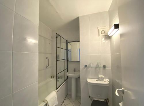 a white bathroom with a toilet and a sink at Normandy Hotel (Near Glasgow Airport) in Paisley