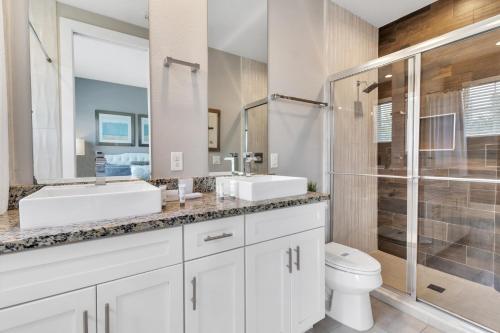 Baño blanco con 2 lavabos y aseo en Lovely 4 Bedrooms, 4 Bathrooms House Near Disney, en Orlando