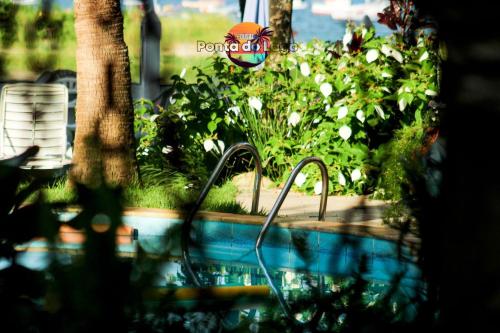 a swimming pool with a garden with flowers at Pousada Ponta do Lago in Florianópolis