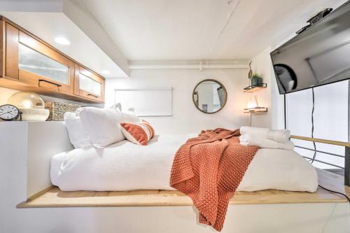 a bedroom with a white bed with an orange blanket on it at Chic SLC Downtown Studio Loft Walk to Shops in Salt Lake City