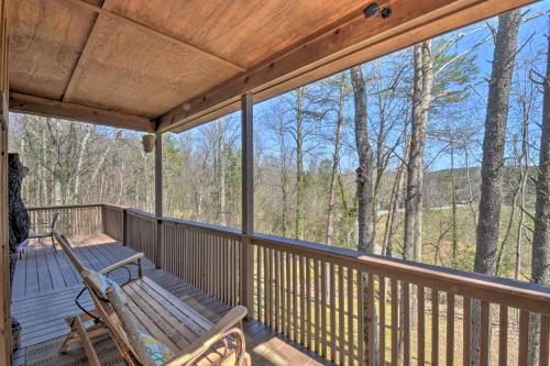 a porch with a bench and a view of the woods at Helen Cabin with Deck and Hot Tub Less Than half Mi to Main St in Helen