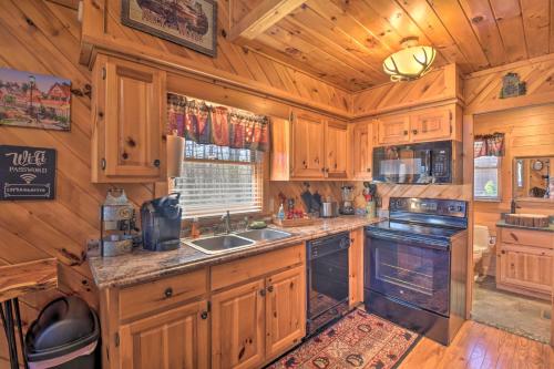 a kitchen with wooden cabinets and a stove top oven at Helen Cabin with Deck and Hot Tub Less Than half Mi to Main St in Helen