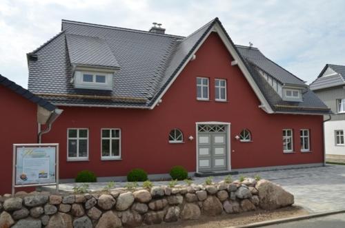 ein rotes Haus mit einer Steinmauer davor in der Unterkunft Landhaus Hagenblick - Apt. 02 in Alt Reddevitz