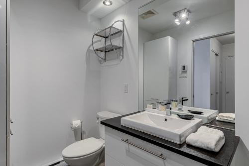 a white bathroom with a sink and a toilet at Les Immeubles Charlevoix - Le 760-631 in Quebec City