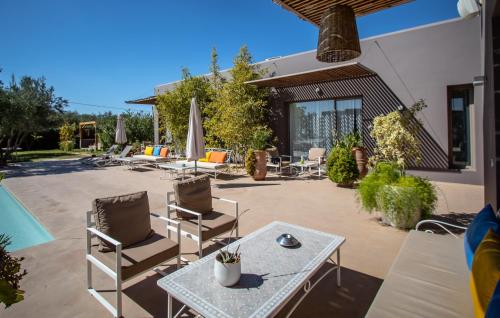 um pátio com cadeiras, uma mesa e uma piscina em Villa Jardins D'Isa em Marrakech