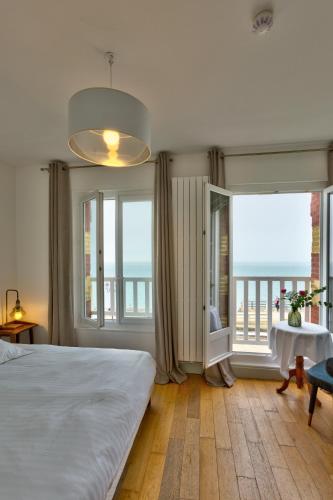 une chambre avec un grand lit et de grandes fenêtres dans l'établissement Hotel Le Rayon Vert, à Étretat