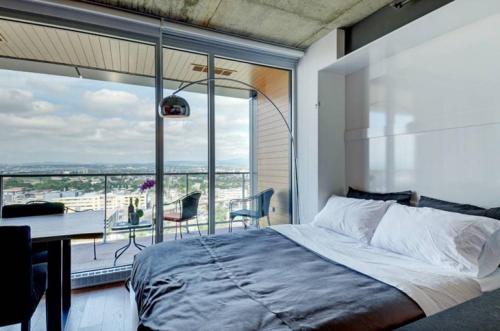 a bedroom with a bed and a desk and a large window at Les Immeubles Charlevoix - Le 760-631 in Quebec City