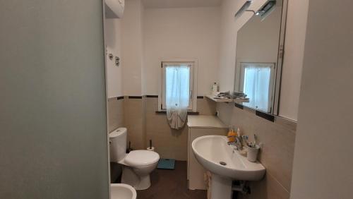 a white bathroom with a toilet and a sink at Salice ottimo trilocale con terrazza pranzabile in Marina di Castagneto Carducci