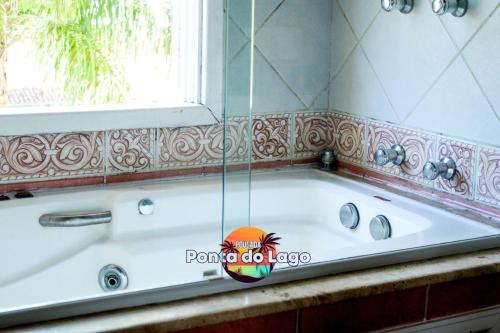 a bath tub in a bathroom with a window at Pousada Ponta do Lago in Florianópolis