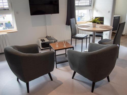 a living room with chairs and a table and a tv at Le Nid des Coucous in Pulversheim