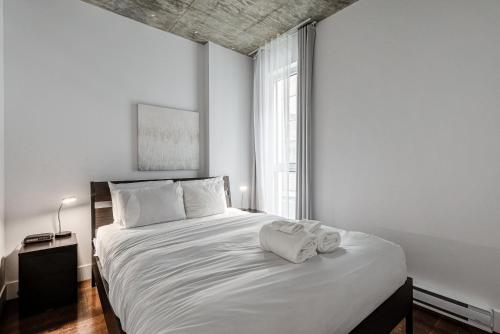 um quarto com uma cama branca com duas toalhas em Les Immeubles Charlevoix - Le 760207 em Cidade de Quebec