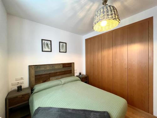 1 dormitorio con cama y lámpara de araña en Apartament La Gisca, en Valencia de Aneu