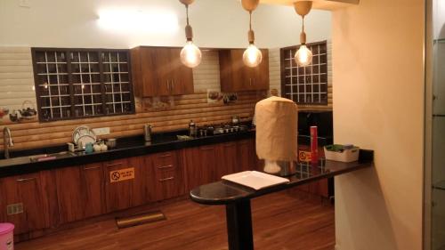 Una cocina con gabinetes de madera y una encimera negra. en NanDha Illam- The Courtyard Heritage HomeStay Yelagiri Hills, en Yelagiri
