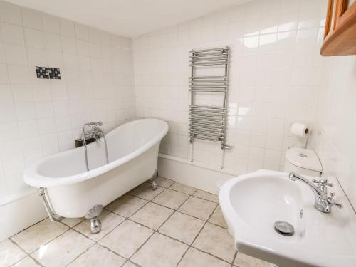 a white bathroom with a tub and a sink at The Nook in Llanfyrnach