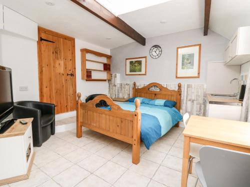 a bedroom with a wooden bed and a kitchen at The Nook in Llanfyrnach