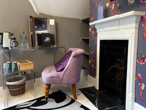 einen lila Stuhl im Wohnzimmer mit Kamin in der Unterkunft Miller of Mansfield in Goring