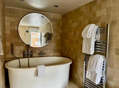 a bathroom with a large tub and a mirror at The Miller of Mansfield in Goring