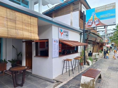 a building with tables and stools outside of it at Komodo Indah Hotel in Labuan Bajo