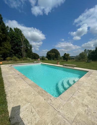 une piscine avec de l'eau bleue dans une cour dans l'établissement LA FERME DE VILLENEUVE, à Saint-Antoine