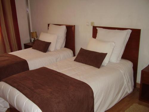 a hotel room with two beds with white and brown pillows at Casa Morgado in Almeida