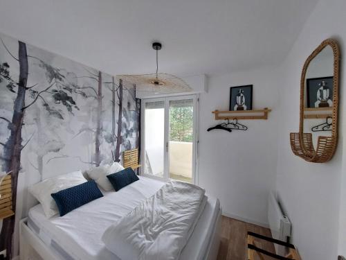 une chambre avec un lit blanc avec des oreillers bleus dans l'établissement Les 3 mouettes à Cabourg - côte normande, à Cabourg