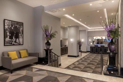 a lobby with a couch and vases with flowers at The Cavendish London in London
