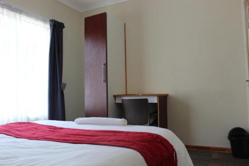 a bedroom with a bed and a chair and a window at ONESI Guest House in Maseru