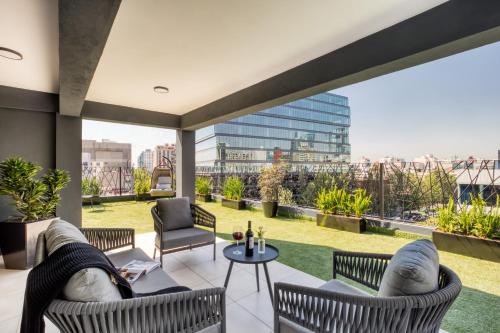 a patio with chairs and tables and a view of the city at ULIV Apartments El Ángel in Mexico City