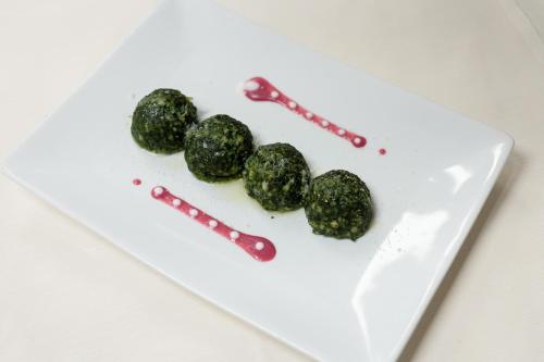 a white plate with three green food items on it at Hotel Fanes Suite & Spa in Moena