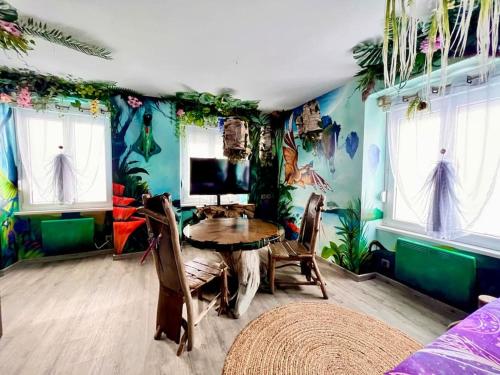 uma sala de jantar com uma mesa num quarto com papel de parede tropical em Avataar - L'arbre de Pandoraa em Belfort