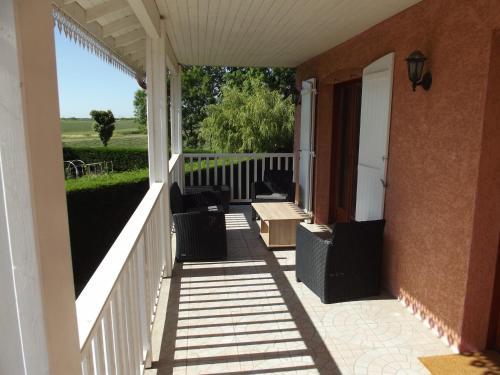 a porch of a house with chairs and a fence at Grand Appartement avec cheminée dans maison, parking gratuit in Mionnay