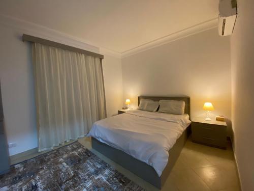 a bedroom with a bed with two lamps and a window at Renoviertes Luxusapartment Sunny Lakes 1 Sharm El-Sheikh nun auch für Langzeitmieter buchbar in Sharm El Sheikh