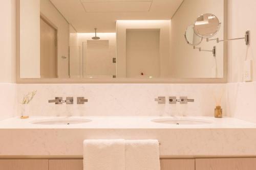 a bathroom with two sinks and a large mirror at Palm Tower St. Regis Amazing view high-end Studio in Dubai