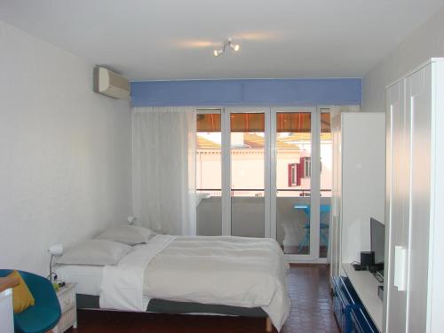 1 dormitorio con cama blanca y ventana en ACCI Cannes Les Yuccas, en Cannes