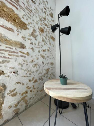 a table with a lamp on it next to a wall at Le Pyrénéen - L'industriel - Maison Cosy in Cazaubon