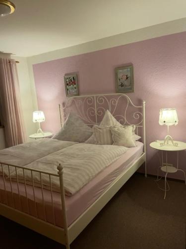 a bedroom with a bed with pink walls and two lamps at Gästehaus Chalet-Perle in Bad Füssing