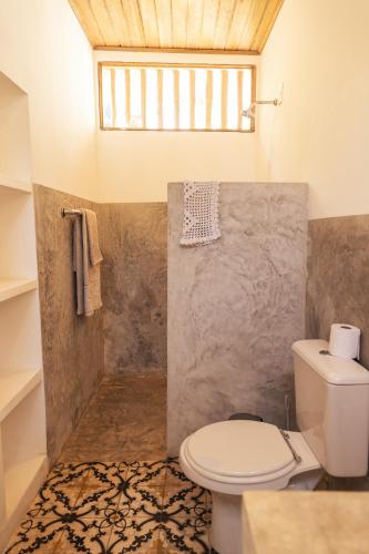 a bathroom with a white toilet and a window at Casa na Lagoa in Paracuru