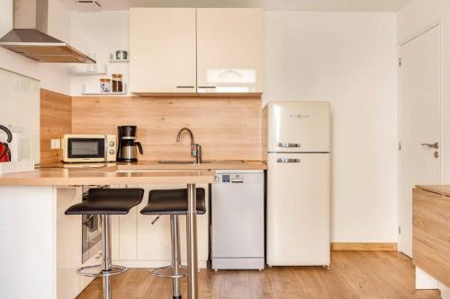 eine Küche mit einem weißen Kühlschrank und 2 Barhockern in der Unterkunft Maison tourangelle chic & cosy avec cour in Tours