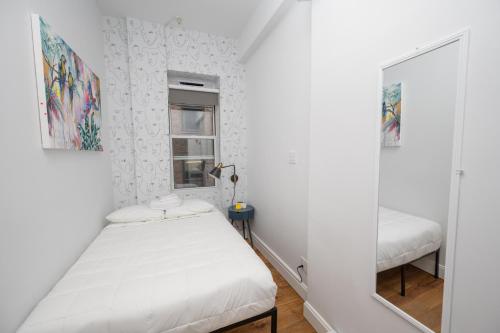 a small bedroom with a bed and a mirror at The Flat NYC in New York