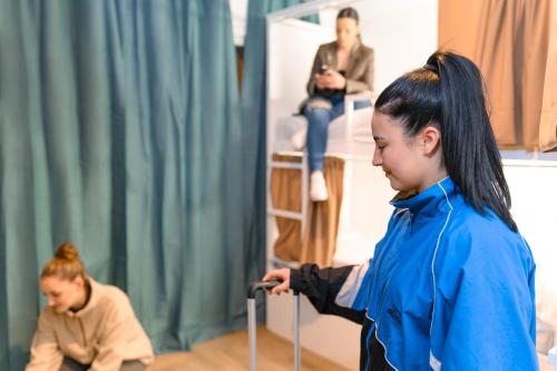 a woman is holding a suitcase while another woman sits at VAD HOSTEL ALICANTE in Alicante