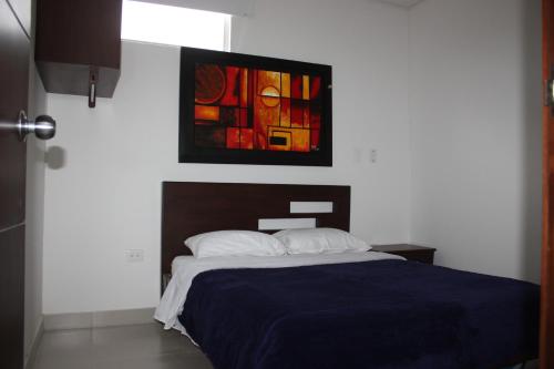 a bedroom with a bed and a painting on the wall at Hotel Las Piedras San Jose in San José de Isnos