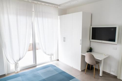 a white room with a desk and a tv and a window at A CASA DI FIBI in Salerno