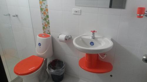 baño con aseo rojo y lavamanos en Hotel Las Piedras San Jose, en San José de Isnos