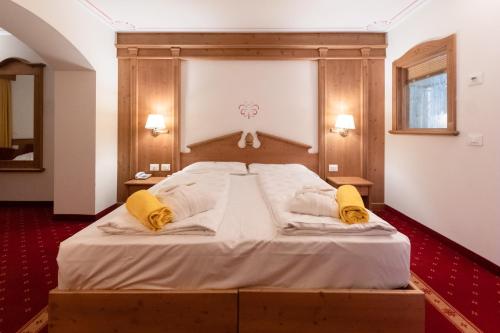 a bedroom with a large white bed with yellow pillows at Hotel Fanes Suite & Spa in Moena