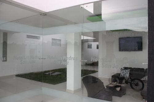 a glass wall in a room with a chair and a television at Hotel Las Piedras San Jose in San José de Isnos