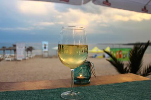 a glass of wine sitting on a table near the beach at Свети Никола Каваците in Sozopol