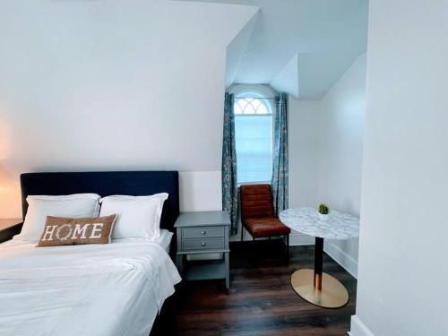 a bedroom with a bed and a chair and a window at Phillips Academy Andover Two-Bedroom Apartment and Free Parking in Andover