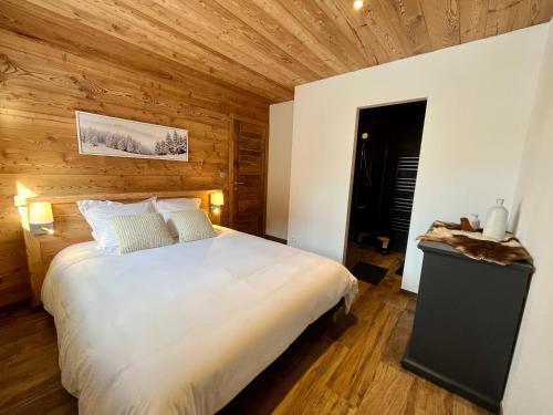a bedroom with a white bed and wooden walls at Appartement les Clochettes 1 - Pied des pistes in Les Deux Alpes