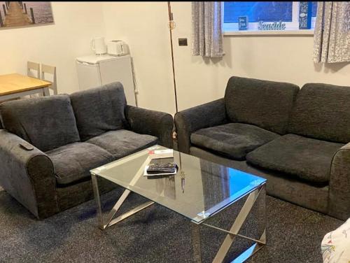 uma sala de estar com dois sofás e uma mesa de vidro em Sea Front Apartment With Massage Shower NETFLIX Great Location em Bridlington